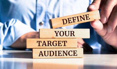 Close up on businessman holding a wooden block with "Define Your Target Audience" message