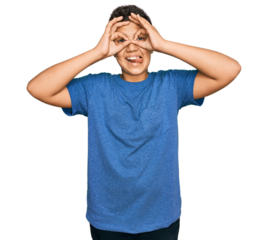 Teenager hispanic boy wearing casual clothes doing ok gesture like binoculars sticking tongue out, eyes looking through fingers. crazy expression.