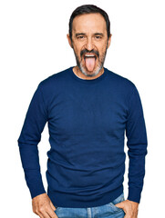 Middle age hispanic man wearing casual clothes sticking tongue out happy with funny expression. emotion concept.