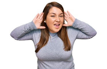 Beautiful brunette plus size woman wearing casual clothes trying to hear both hands on ear gesture, curious for gossip. hearing problem, deaf