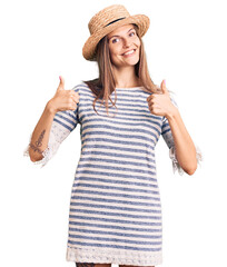 Obraz na płótnie Canvas Beautiful caucasian woman wearing summer hat success sign doing positive gesture with hand, thumbs up smiling and happy. cheerful expression and winner gesture.