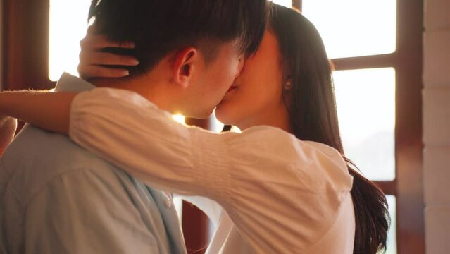 Asian young man and woman kissing each other in living room at home. 