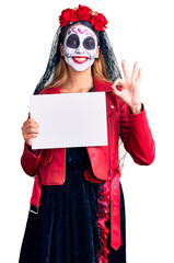 Woman wearing day of the dead costume holding blank empty banner doing ok sign with fingers, smiling friendly gesturing excellent symbol