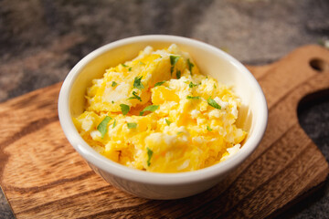 Scrambled eggs on bowl, wooden table, close up view