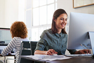 Getting work done with a positive attitude. Shot of colleagues working on their computers in an...