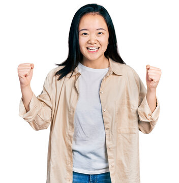 Young chinese woman wearing casual white t shirt and jacket celebrating surprised and amazed for success with arms raised and open eyes. winner concept.