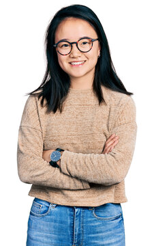 Young chinese woman wearing casual sweater and glasses happy face smiling with crossed arms looking at the camera. positive person.