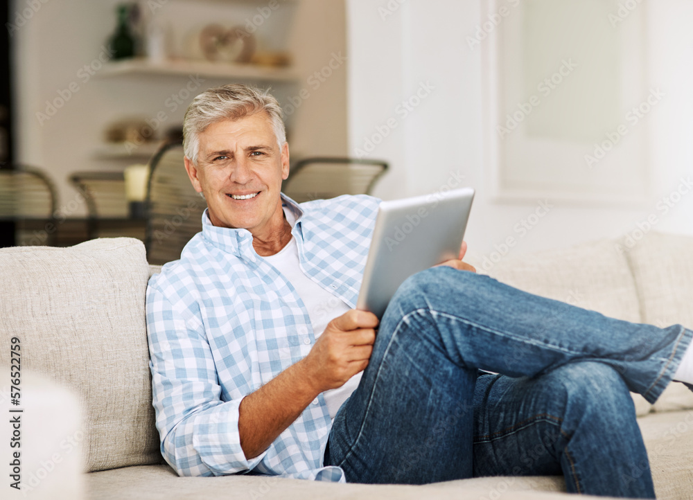 Aufkleber killing time online. shot of a mature man using his digital tablet while relaxing on his sofa at hom