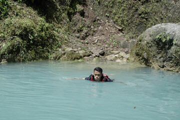 Fototapeta premium tourists enjoying a natural swimming pool, at the tourist spot Kedung Pedut, Yogyakarta, Indonesia. The unique and fresh river is blue