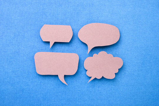 Gray speech bubble or text box made of color paper cut on blue paper background.