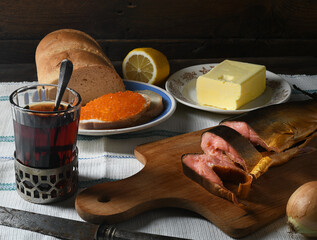 Red caviar, butter and fish with tea on a wooden background