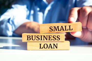 Close up on businessman holding a wooden block with "Small Business Loan" message