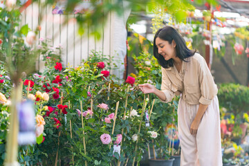 Happy Asian woman choosing and buying potted plant at plant shop street market on summer vacation. Attractive woman enjoy hobbies and leisure activity lifestyle growing plant and flower at home.