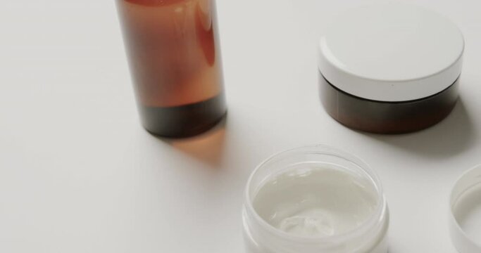 Close up of cream tubs and glass bottle with copy space on white background