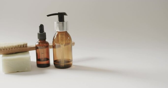 Close up of glass bottles with pumps, soap, brush and copy space on white background