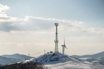 눈 내린 산 위 풍차와 통신탑