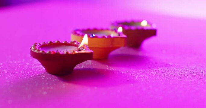 Close up of burning colourful candles celebrating diwali on purple background