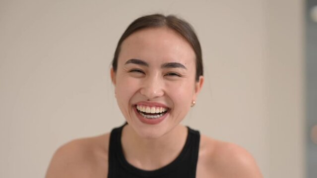 Portrait of a grimacing and smiling Asian woman on a white background.