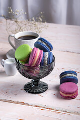 Colorful macaroons in a glass vase on a white table close-up