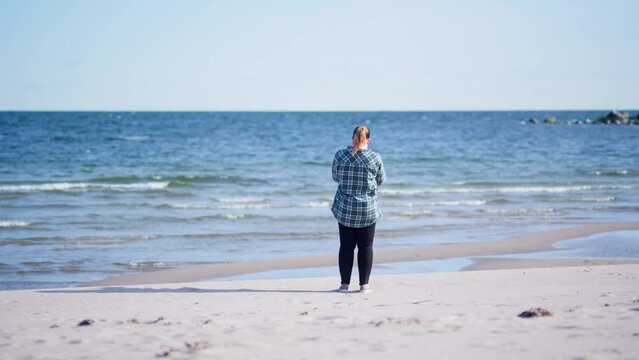 Girl standing on the beach taking photos of the ocean