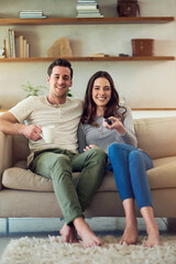 Movie date on the home front. Portrait of a happy young couple relaxing on the sofa and watching tv...