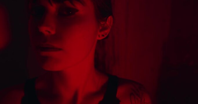 Deep eyes of attractive woman lit by red neon lights, close up face view