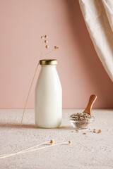 Sunflower seed milk on bottle on beige background with plant. copy space. Raw diet meal. Healthy...