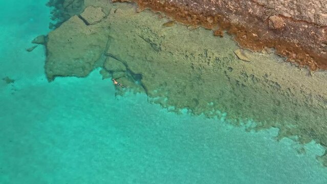 Person snorkelling along rocky shorelines in Spain on summers day