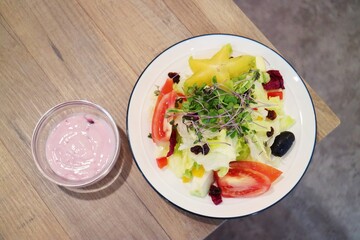 A colorful salad filled with a variety of vegetables and fruits, with blueberry salad dressing