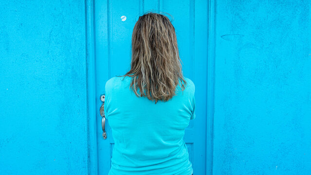 Anonymous Woman Seen From The Back With Blonde Hair And Blue T Shirt In A Blue Background