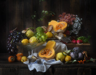Autumn still life. Grapes, pumpkin, persimmon, figs, pears, mushrooms on a wooden background. Rustic style.