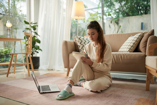Girl sitting on floor at home and filling gratitude journal