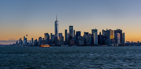 Manhattan at Sunrise with Sun reflecting on skyscrappers and Staten ISland Ferry in the foreground
