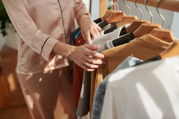 Obraz premium Cropped image of young woman in satin pajamas choosing outfit for the day