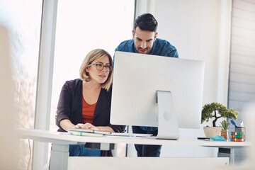 Combining creative talent and technology for a winning project. Shot of a young man and woman using a computer together in a modern office.