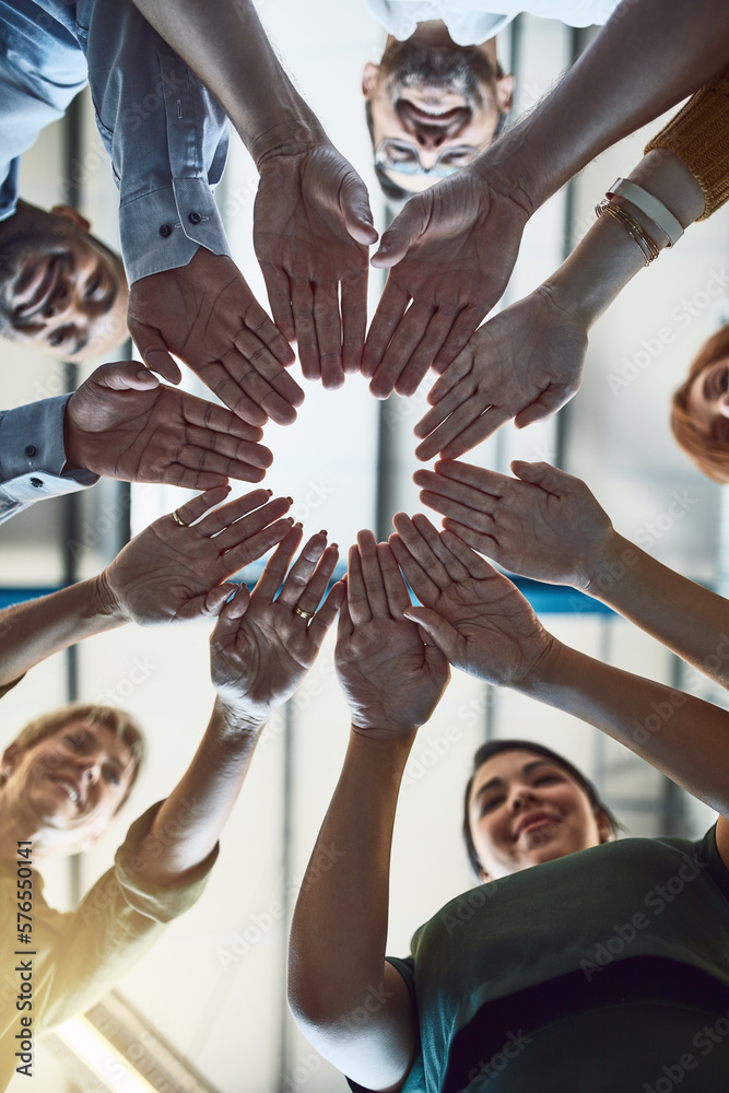 Poster success is in the hands of their team. low angle shot of a group of colleagues joining their hands i