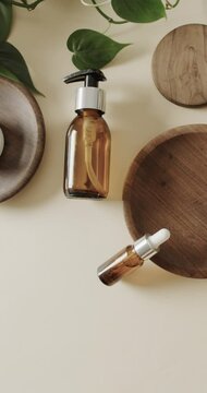 Vertical video of close up of glass bottles and wooden plates and copy space on beige background