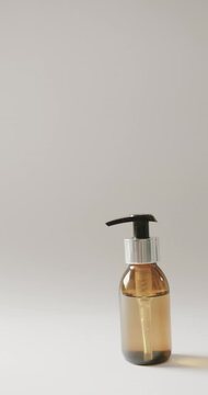 Vertical video of close up of glass bottle with pump and copy space on white background