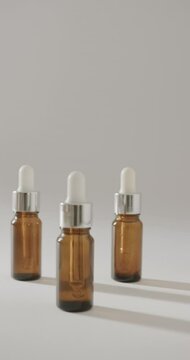 Vertical video of close up of glass bottles with pumps and copy space on white background