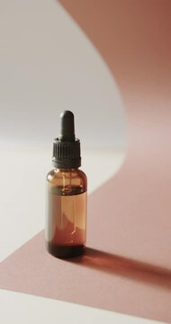 Vertical video of close up of glass bottle with pump and copy space on pink background