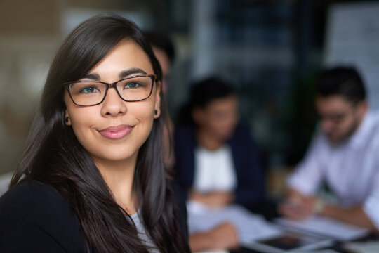 Shes A Standout In The Office. Portrait Of A Smiling Young Businesswoman In An Office With Colleagues In The Background.