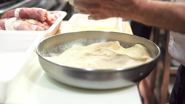 Close-up of an experienced chef breading steaks and dipping them in egg for frying