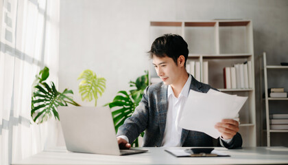 Young business man working at office with laptop, tablet and taking notes on the paper..