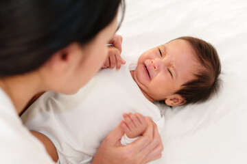 mother with newborn baby crying on bed