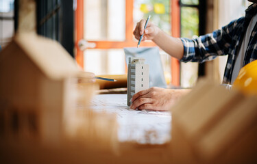 business man hand working and laptop with on on architectural project at construction site at desk