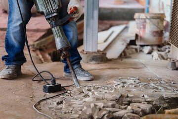 labor using a jackhammer to break up concrete floor