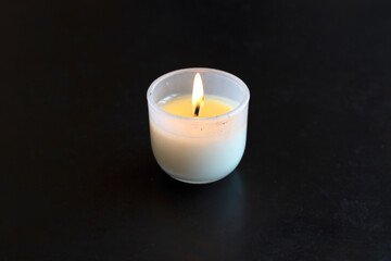 Fototapeta na wymiar Burninng candle is on black table in the dark.