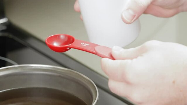 Adding fragrant oil to melted wax for homemade candle project