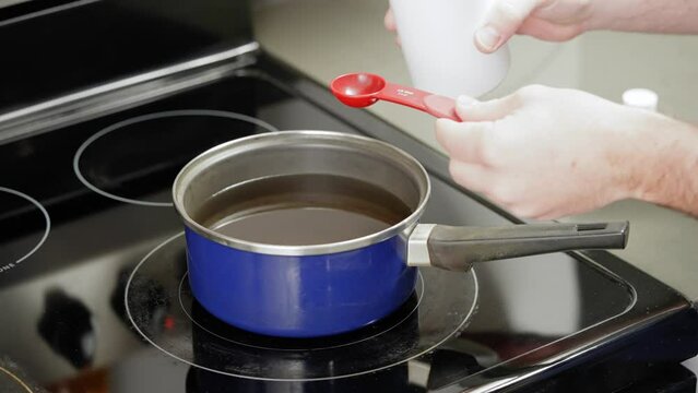 Adding fragrant essential oil to melted wax for candle making at home