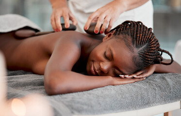 Black woman, hot stone massage and masseuse, hands and zen with holistic therapy and spa treatment. Calm, peace of mind and female, healing and stress relief with self care at wellness resort